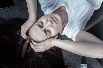 Emotional stress. Top view of beautiful nervous troubled woman touching her hair while weeding and...