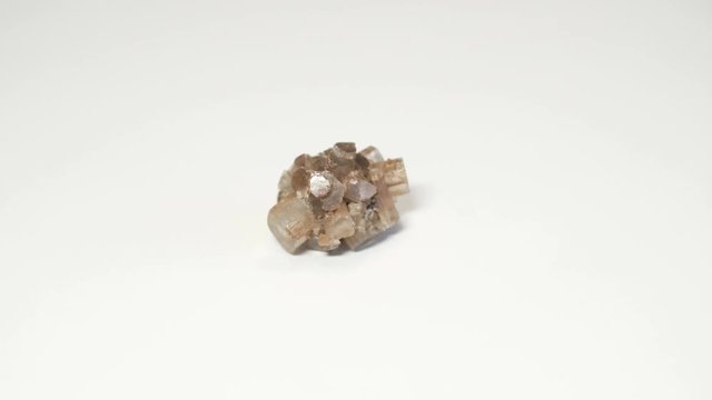 Macro shot of cluster of aragonite mineral isolated over white background and spinning around
