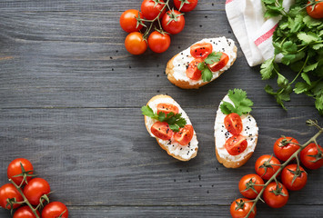 Bruschetta with ricotta cheese, cherry tomatoes and cilantro on a wooden background       