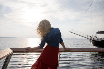 Fototapeta premium Beautiful woman in red dress on the background of the sea.