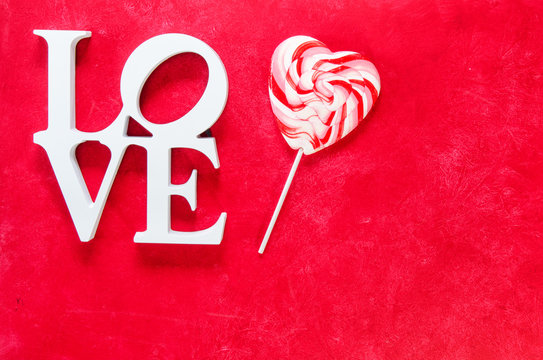 White word love on a red background with a lollipop and  copy space