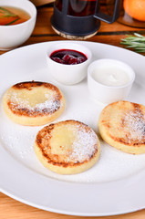 Traditional russian breakfast fried cottage cheese with cherry jam, sour cream and black tea. Top view cheese pancake, close.