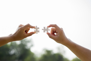 Closeup hands of woman and man connecting jigsaw puzzle