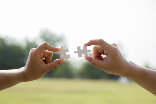 Closeup hands of woman and man connecting jigsaw puzzle