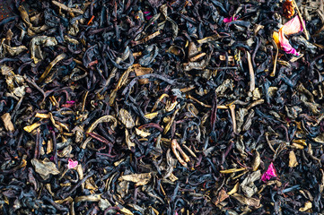 black tea as background with dry rose petals