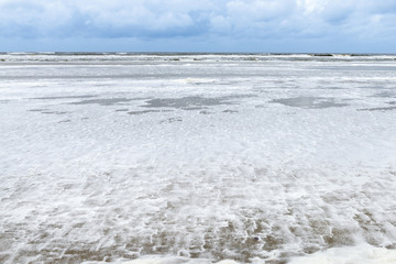 Deutschland, Niedersachsen, Ostfriesland, Juist, schaumiges Meerwasser am Strand.