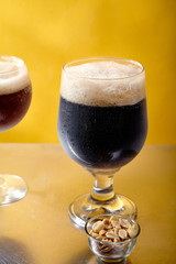 Ale and stout beer in glasses with snacks and sauce on metallic and yellow background