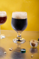 Ale and stout beer in glasses with snacks and sauce on metallic and yellow background