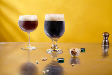 Ale and stout beer in glasses with snacks and sauce on metallic and yellow background