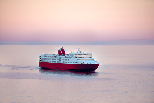 Sunset and a blue white ferry boat in greek islands