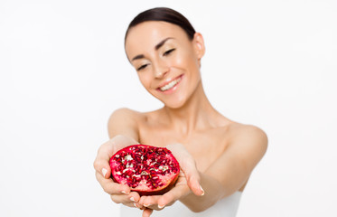 Bright and emotional beautiful woman with half a pomegranate in hands posing in front of the camera. Fruit is health.