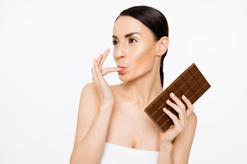 Naklejka premium Natural chocolate. Beautiful cheerful young woman holding a tile of black chocolate in hands on a white background
