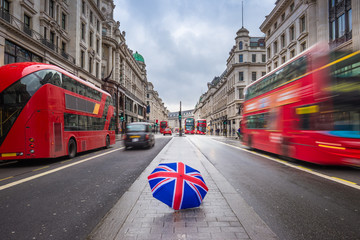 London, England - British umbrella at busy Regent Street with iconic red double-decker buses and...