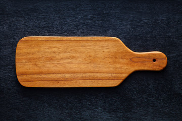 Handmade wooden cutting board on black board.