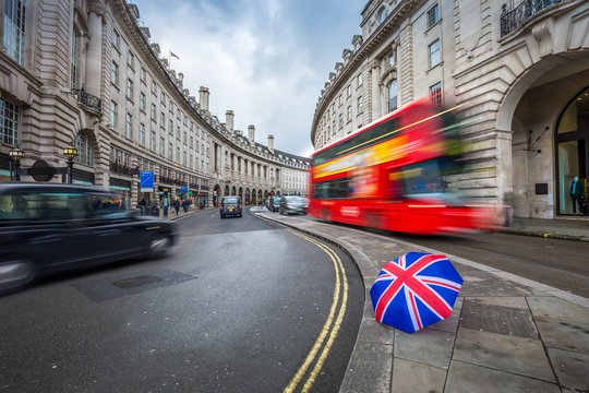 London, England - Iconic red double-decker bus and black taxies on the move on Regent Street with british umbrella