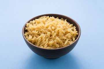 Spiral pasta in bowl on blue background