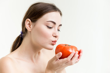 Beautiful girl is showing and kiss a big red tomato healthy high nutrition vegetable good for skin