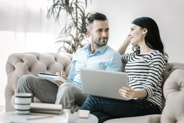 Love during work. Pleasant gay two colleagues looking at each other while working and posing on sofa