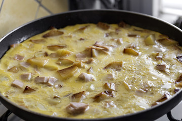 Cooking omelette made with eggs, potatoes and ham