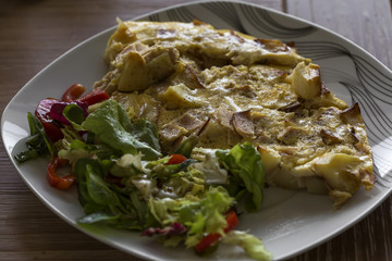 Omelette with ham and potatoes on plate with salad