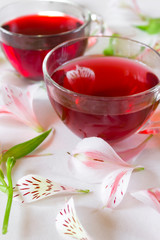 Two cups of red tea and petals of flowers on a white background. Place for text. Creative layout. Concept. Design. Close up