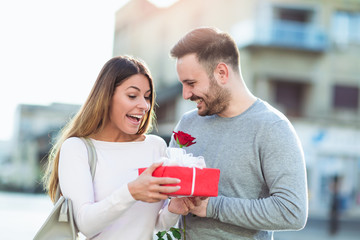 Man surprises woman with a gift and rose in the city