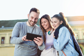 Group of smiling friends with digital tablet outdoor