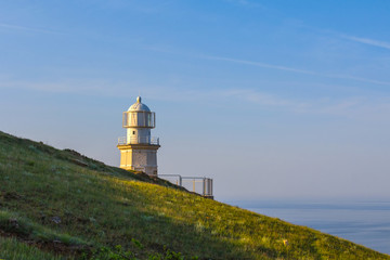 Fototapeta na wymiar lighthouse on a marine cape slope at the evening
