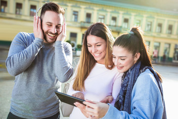 Group of smiling friends with digital tablet outdoor