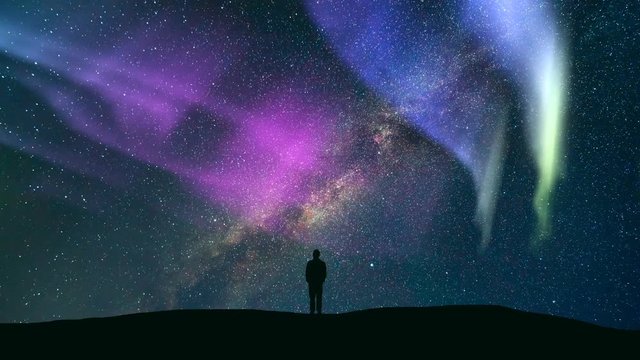 The man standing against the meteor shower with a northern light. time lapse