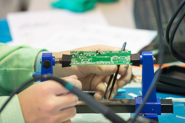 A person solder the parts of the chip with a soldering iron with tin