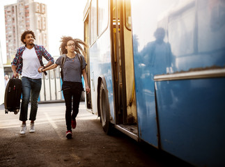 Young couple is rushing to catch a blue bus while holding each others hands.