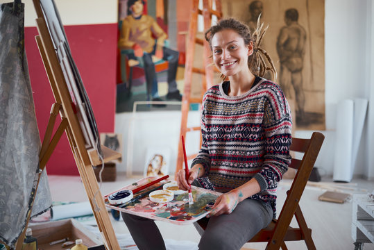 Woman artist painting on canvas in her atelier