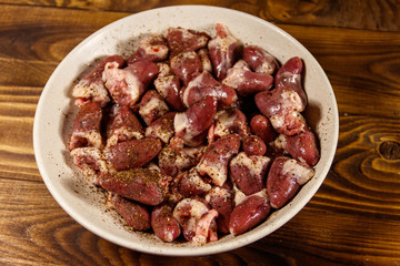 Raw chicken hearts on wooden table