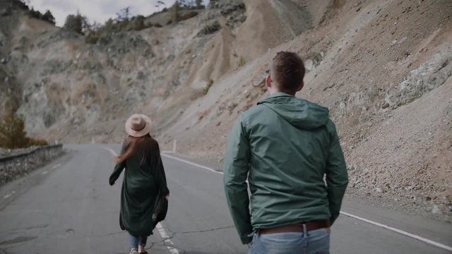 Stylish young couple walking on the mountain road