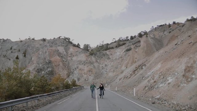 Stylish young couple walking on the mountain road