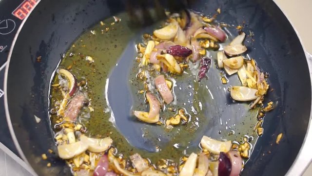 Cooking onions in a frying pan. Clip. Frying onions in a cast iron pan