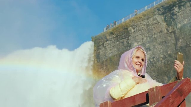 A happy tourist photographs himself against the background of Niagara Falls