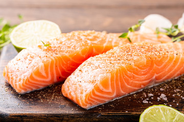 Fresh raw salmon fillet with aromatic herbs, spices on old wooden background.