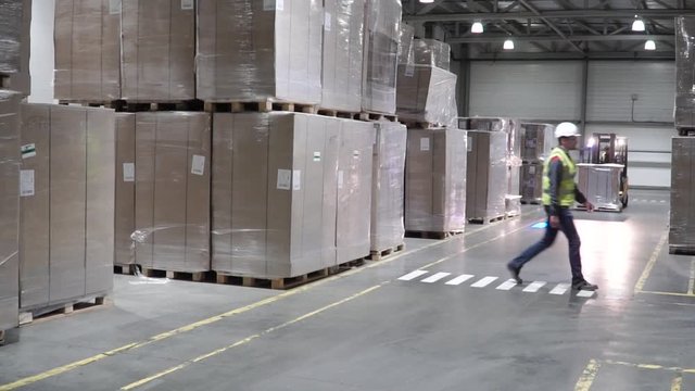 Lift truck in factory. Clip. Wholesale logistic, loading, shipment and people concept - man with loader carrying cargo at warehouse