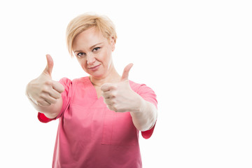 Attractive female nurse wearing pink scrubs showing double like gesture