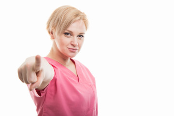 Attractive female nurse wearing pink scrubs pointing camera