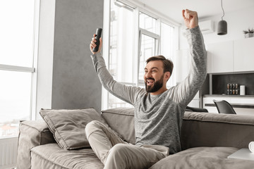 Portrait of an excited young man holding TV remote control