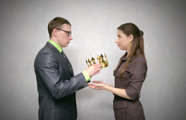 The businessman holds the gold crown as symbol of power and giving it to his receiver. Change of power. Transfer of authority. Award ceremony for the first place winner. Coronation.