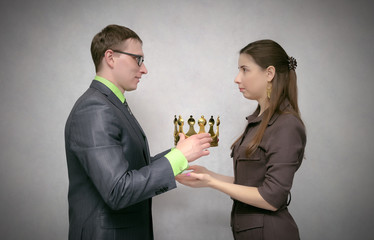 The businessman holds the gold crown as symbol of power and giving it to his receiver. Change of power. Transfer of authority. Award ceremony for the first place winner. Coronation.