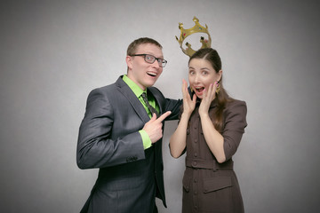 The leader man dresses the golden crown on the winner head isolated on gray background. Award ceremony for the first place winner. Coronation.