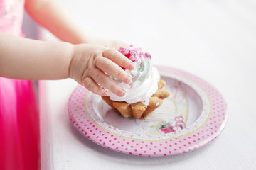 Baby girl hand holding the first birthday cake