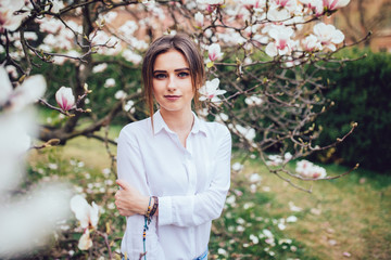 beautiful young woman near the blossoming spring tree. Magnolia blossom.