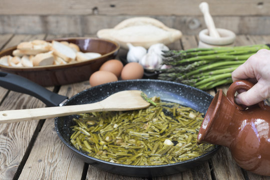 Cocinando una sopa de esp&aacute;rragos, persona vierte agua para la sopa
