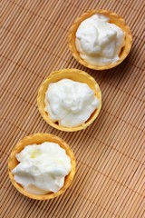four cakes with cheese cream on a bamboo napkin